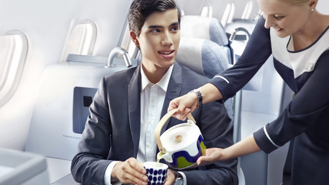 Finnair flight attendant pouring green tea to a man in business class
