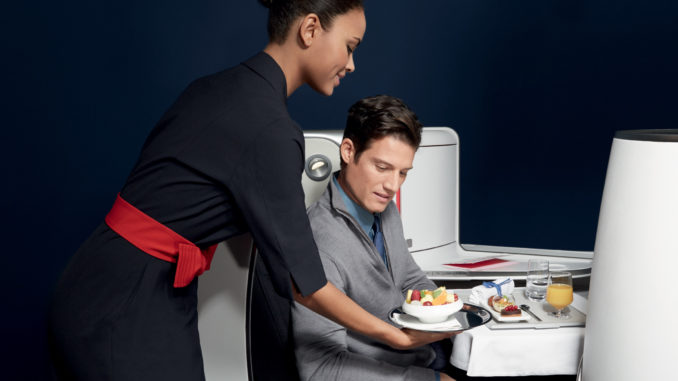 Air France new business class seat - male passenger during meal service being served by a flight attendant