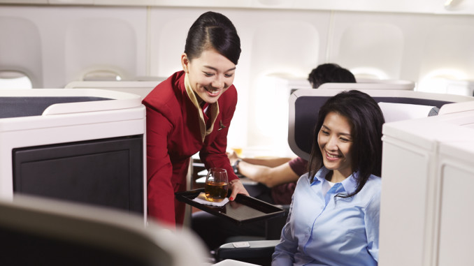 Cathay Pacific Business Class cabin and seat with flight attending serving drink