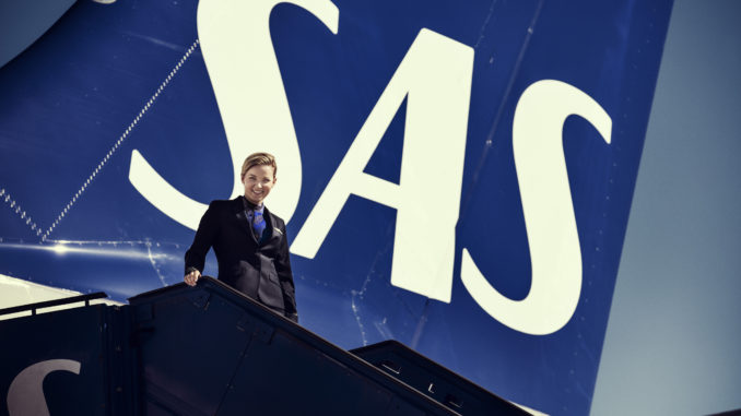 SAS flight attendant in the new uniform in front of aircraft tail with logo